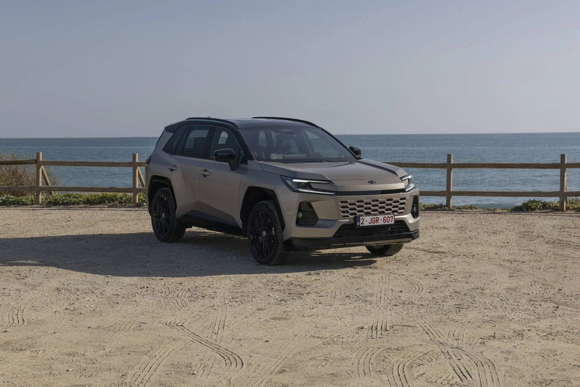 Toyota RAV4 VI 2025 exteriér přední bok záběr na pláži u moře, šedý SUV s černými koly a maskou, čelní pohled, záběr z nízkého úhlu